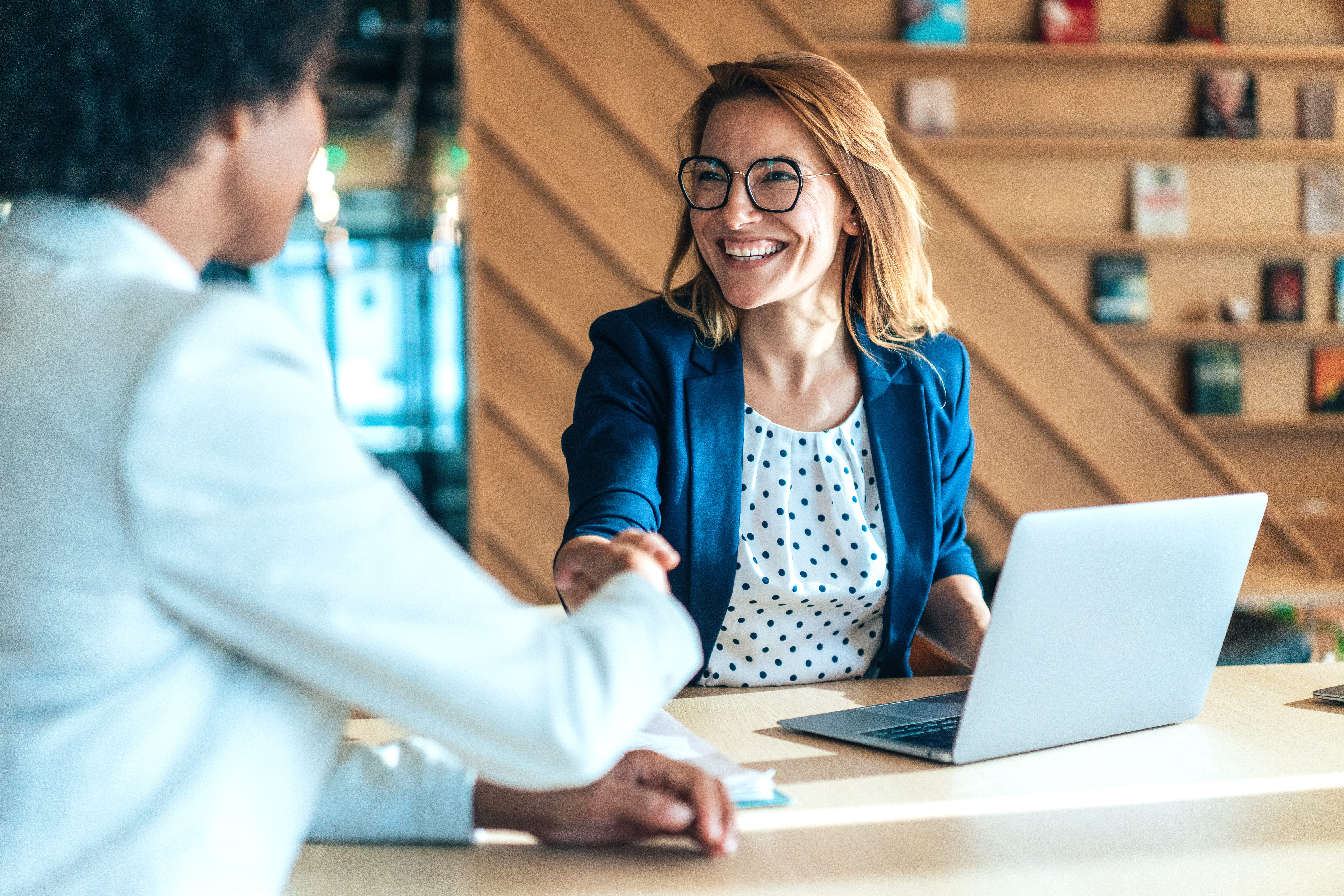 Business people shaking hands in the office. Group of business persons in business meeting. Two entrepreneurs on meeting in board room. Corporate business team on meeting in modern office. Female manager discussing new project with her colleagues. Company owner on a meeting with her employee in her office.