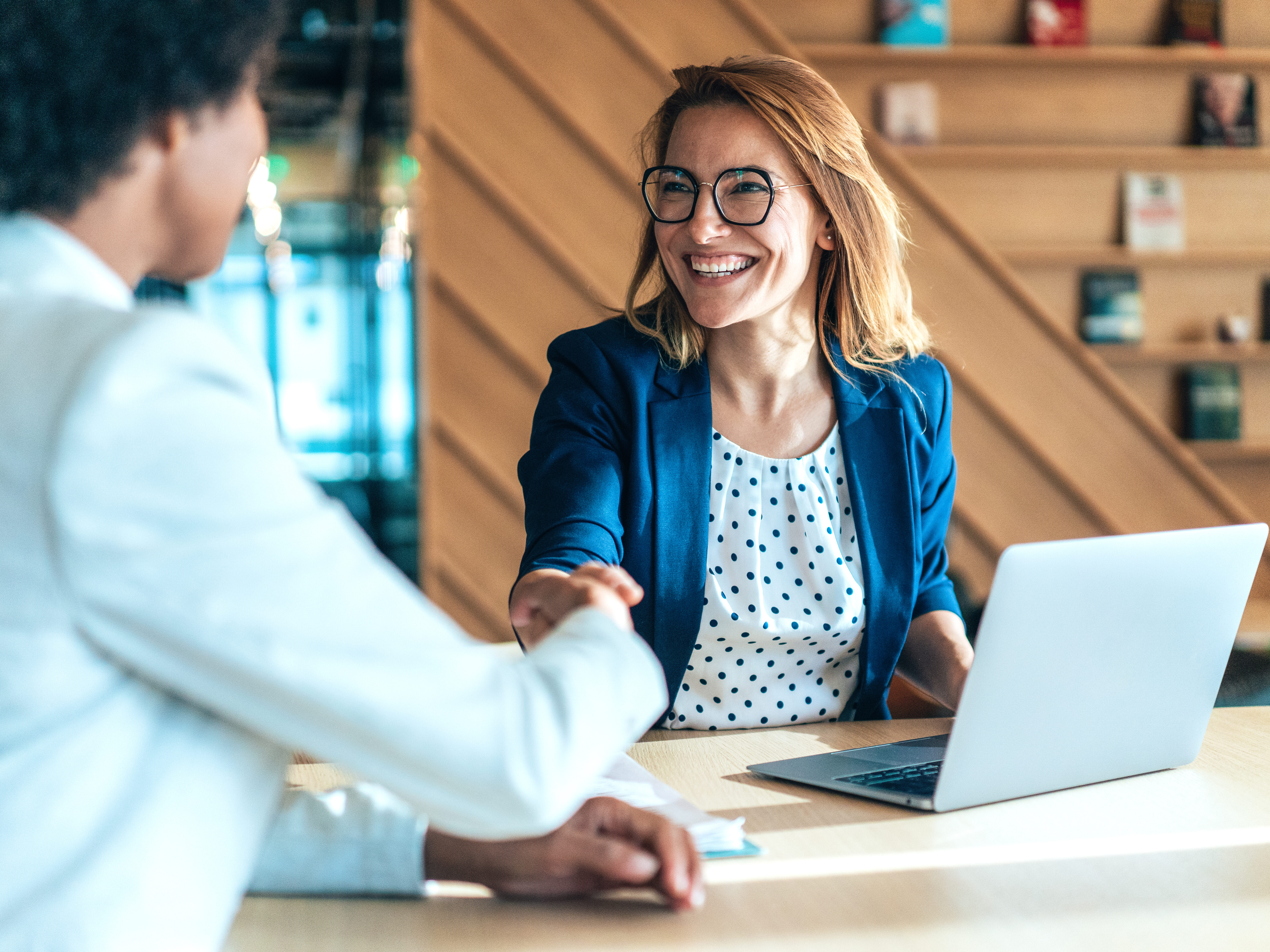 Business people shaking hands in the office. Group of business persons in business meeting. Two entrepreneurs on meeting in board room. Corporate business team on meeting in modern office. Female manager discussing new project with her colleagues. Company owner on a meeting with her employee in her office.